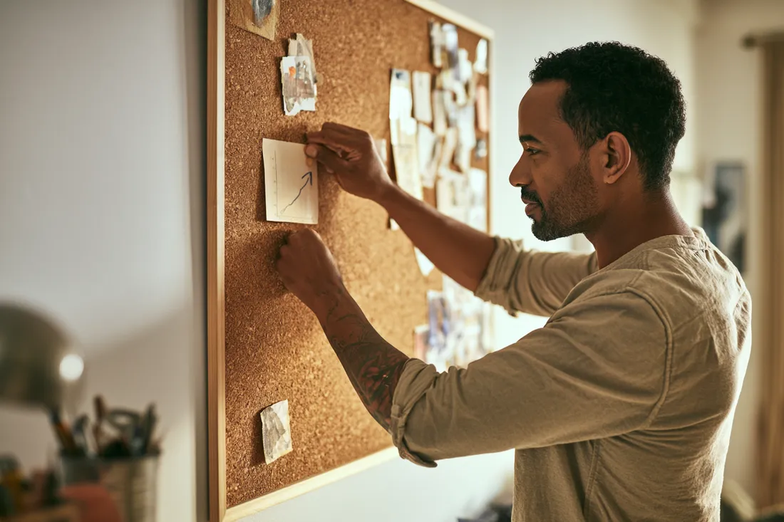 Man pinning steady progress notes to a board, tracking his rebuild