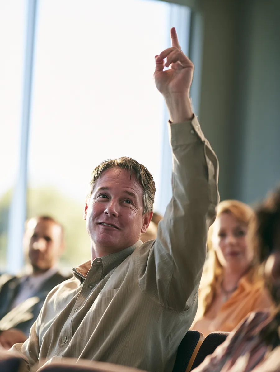 Attendee raising a hand to ask a question during a small financial workshop